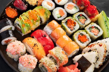 Çeşitli suşi nigiri ve maki büyük set. Ton balıklı, yengeçli, somonlu ve koyu arkaplanda yuvarlanan bir çeşit Japon suşisi. Üst yaşam