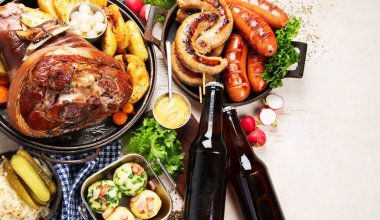 Geleneksel Alman yemeği, bavyera sosisi, kraker, patates, lahana turşusu, arka planda bira bardağı. Üst Manzara. Boşluğu kopyala.