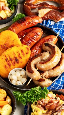 Çeşitli Avustralya yemekleri... Şnitzel, sosis, patates, Knodel, salata ve soslar hafif arkaplanda. Üst görünüm.