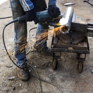 Metal işleri. Adam bir çelik parça bir açı öğütücü ile biler.