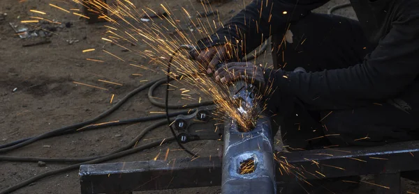 Metal work. Man grinds a steel piece with an angle grinder