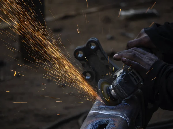 Metal work. Man grinds a steel piece with an angle grinder