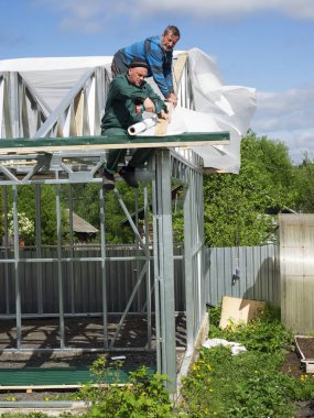 Beyaz erkekler çatı kaplama işi gerçekleştirir. Nem bariyeri montajı