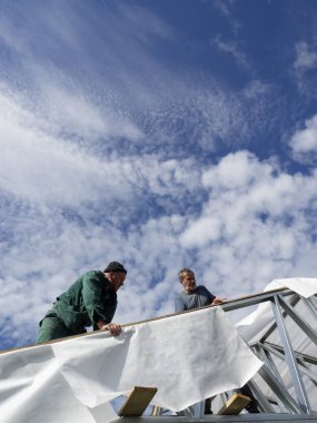 Beyaz erkekler çatı kaplama işi gerçekleştirir. Nem bariyeri montajı