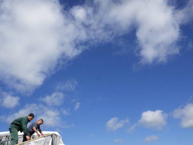 Beyaz erkekler çatı kaplama işi gerçekleştirir. Nem bariyeri montajı