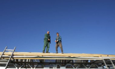 Beyaz erkekler çatı kaplama işi gerçekleştirir. Ahşap ahşap taban tahtası montajı