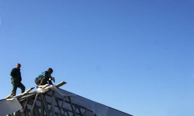 Beyaz erkekler çatı kaplama işi gerçekleştirir. Ahşap ahşap taban tahtası montajı