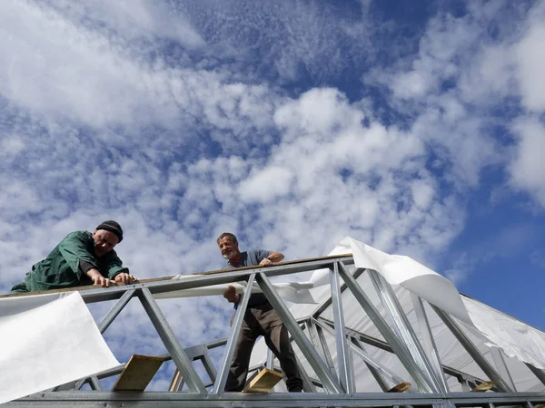Beyaz erkekler çatı kaplama işi gerçekleştirir. Nem bariyeri montajı