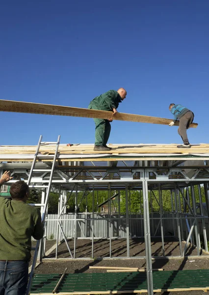 Beyaz erkekler çatı kaplama işi gerçekleştirir. Ahşap ahşap taban tahtası montajı