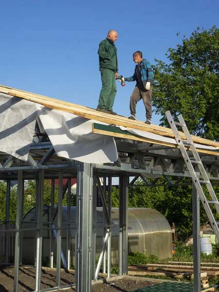 Beyaz erkekler çatı kaplama işi gerçekleştirir. Ahşap ahşap taban tahtası montajı