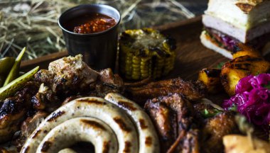 Meze tabağı soğuk et tabağı ile prosciutto, dilim jambon, kurutulmuş et, salam ve roka ahşap arka plan üzerinde kesme tahtası üzerinde yakın. Etli meze