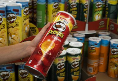Çocuğun elinde Bir paket Pringles Cipsi var.