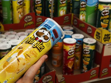 Çocuğun elinde Bir paket Pringles Cipsi var.