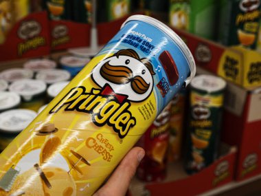 Çocuğun elinde Bir paket Pringles Cipsi var.