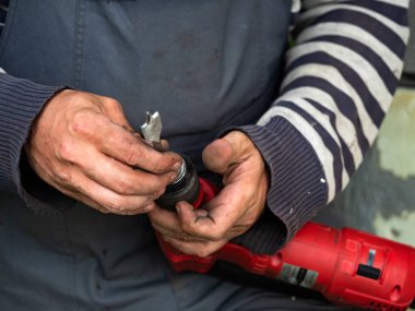 Adam elektrikli matkabın ucuna bir ağaç matkabı yerleştiriyor.
