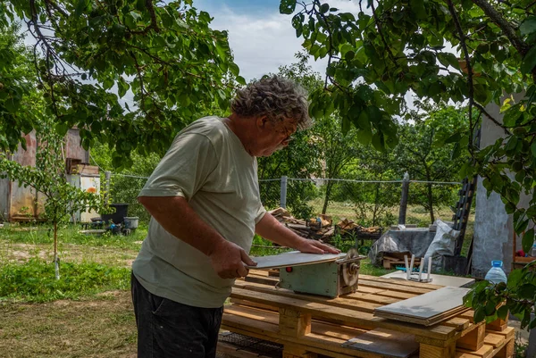 Kaukaski Starszy Mężczyzna Pomocą Piły Tarczowej Cięcia Deski Parkietowej Ogrodzie — Zdjęcie stockowe