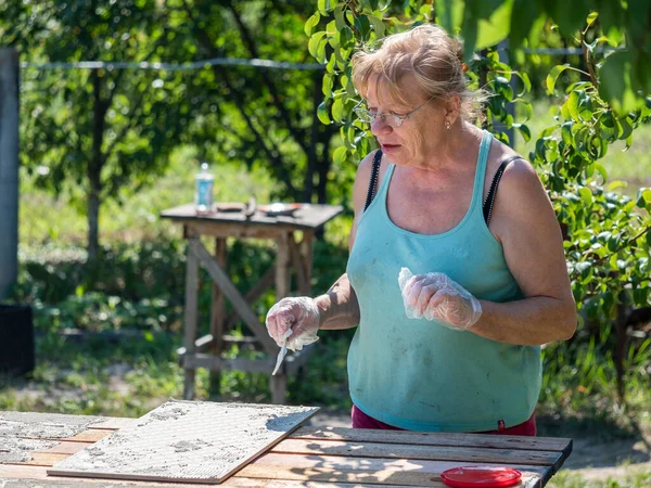 Caucasian Senior Woman Installs Ceramic Tiles Garden Wooden Table — Stock Photo, Image