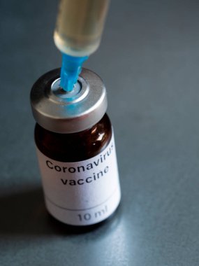 Bu resimde, Coronavirus aşısı olarak etiketlenmiş şişeler ve bir şırınga 