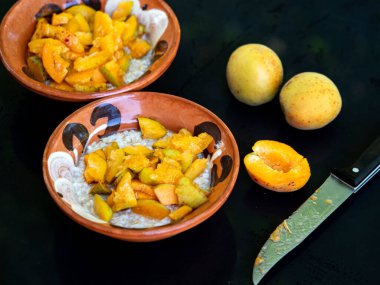 Bahçedeki siyah bir masada kayısılı yulaf ezmesi.