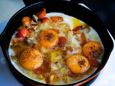 Domatesli çırpılmış yumurta, indüksiyon elektrikli sobada, dökme demir bir tavada kızartılır.