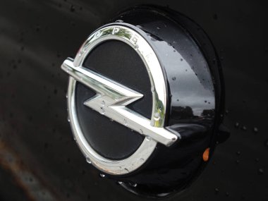 Almanya - 25 Eylül 2025: Merkezi simgesel yıldırımıyla dairesel Opel logosunun çarpıcı bir görüntüsü. Logo siyah ve dokulu bir arka plana karşı parlak krom renginden yapılmış. Amblem ve çevreleyen yüzeyler çok zayıf.