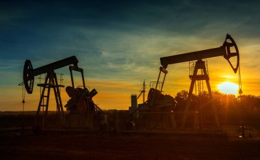 Two working oil pumps silhouette against sunset clipart