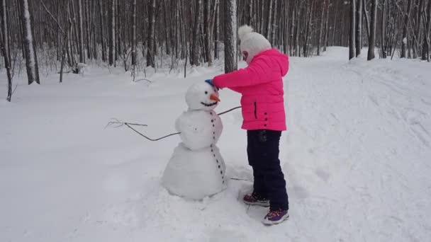 Κοριτσάκι Κάνει Ένα Χιονάνθρωπο Στο Δάσος Χειμώνα — Αρχείο Βίντεο