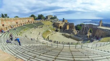 Taormina, İtalya - 15 Mayıs 2018: Taormina, Sicilya, İtalya için antik Yunan tiyatro kalıntıları. Giardini Naxos Coast Körfezi İyon Denizi ve duman arka planda Etna Dağı. Zaman atlamalı. 4k Ultrahd