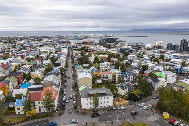 İzlanda 'nın Reykjavik şehrinin resimli hava manzarası. Şehir merkezi, merkez cadde, dağlar ve şehrin ötesindeki okyanus manzarası. Reykjavik 'teki Hallgrimskirkja Katedrali' nin tepesinden görüntü