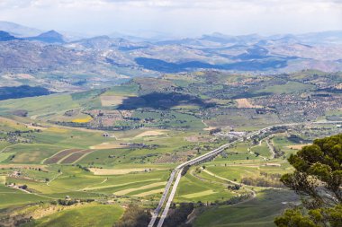 Pitoresk yeşil tepelik Vadisi Enna şehir, merkezi Sicilya, İtalya. Ön plan üzerinde Palermo'ya otobanı A19 Catania üzerinden. Castello di Lombardia görüntülemek
