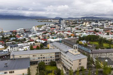 Hava ısmarlayarak şehrin Reykjavik, İzlanda. Şehir merkezinde, dağlar ve okyanus sahne şehir dışında. Reykjavik katedralde tanımlıkHallgrimskirkja tepesinden görüntülemek