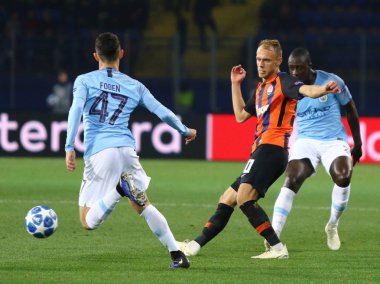 Kharkiv, Ukrayna - 23 Ekim 2018: Serhiy Bolbat Shakhtar Donetsk (C) kavgalar bir top ile Phil Foden Manchester City (L) Osk Metalist Stadyumu'nda kendi Uefa Şampiyonlar Ligi oyun sırasında