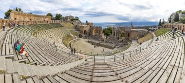 Taormina, İtalya - 14 Mayıs 2018: Taormina, Sicilya, İtalya için antik Yunan tiyatro kalıntıları. Giardini Naxos Coast Körfezi İyon Denizi ve duman arka planda Etna Dağı