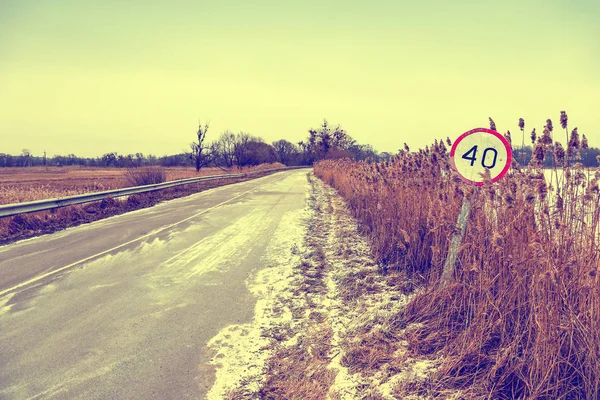 Strada invernale con vecchio segnale di limite di velocità — Foto Stock