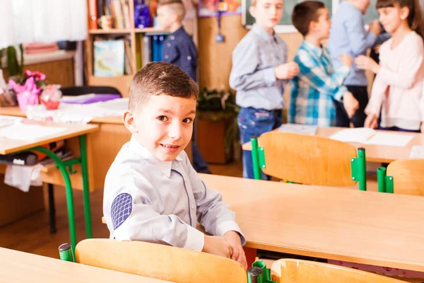 Aranyos fiú ül az asztalon a classrom — Stock Fotó