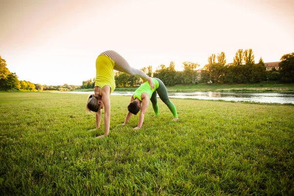 Dos jóvenes hermosas mujeres de pie en pose de acro yoga — Foto de Stock