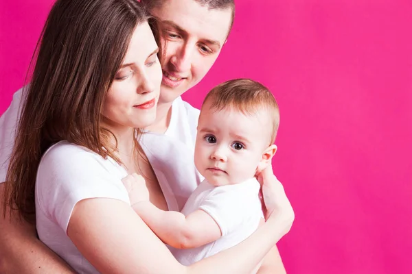 Hermosa familia está posando con su bebé, fondo rosa — Foto de Stock