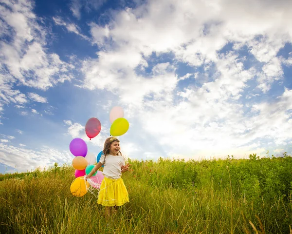 Meisje met ballons tegen blauwe hemel — Stockfoto