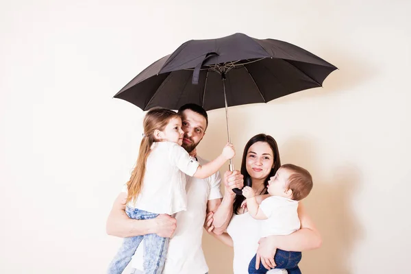 Молодая семья стоит под зонтиком — стоковое фото