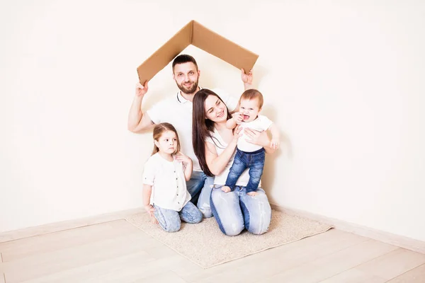 Ευτυχισμένη νεαρή οικογένεια κάτω από μια ασφαλή στέγη, έννοια — Φωτογραφία Αρχείου