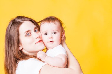Sevimli Genç Anne ve çocuk kameraya, seyir gülümseyerek. Sarı arka plan üzerinde izole