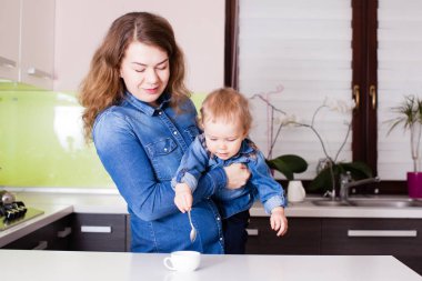 Stirr annesinin kollarında kahve için şirin bebek