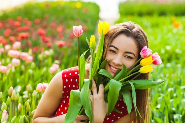 Schöne Frau mit bunten Tulpen — Stockfoto