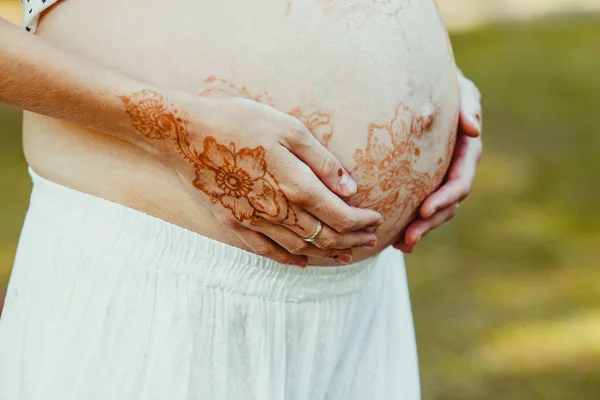 Elegantes manos con mehendi mantenga pintado el vientre embarazada — Foto de Stock