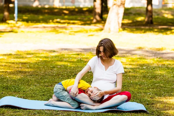 Беременная женщина и ее сын расслабляются после фитнеса на открытом воздухе — стоковое фото