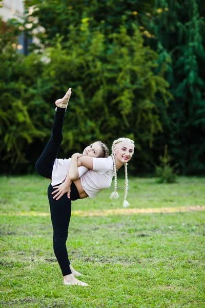 Sportieve moeder en dochter die zich uitstrekt op gras — Stockfoto