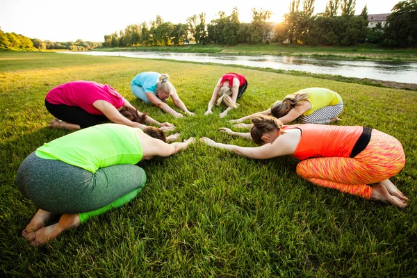 Group of women laying on a grass while practicing yoga — Stock Photo, Image