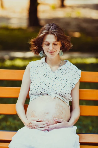 Młoda kobieta w ciąży, usytuowanie na ławce — Zdjęcie stockowe