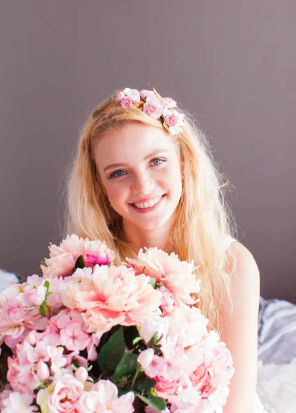 Jovem mulher bonita segura buquê de flores no fundo cinza — Fotografia de Stock