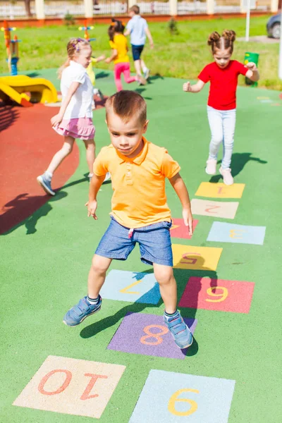 Rapaz salta jogando hopscotch — Fotografia de Stock